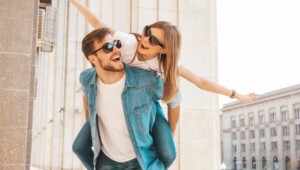 smiling beautiful girl and her handsome boyfriend in casual summer clothes man carrying his girlfriend on the back and she raising her hands 650x410 Економічні новини