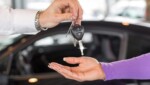 car salesperson handing over keys to new car Економічні новини - головні новини України та світу