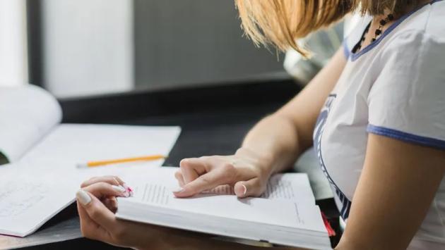 girl sitting at table reading Економічні новини - головні новини України та світу