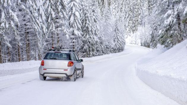 car on the road in the mountains surrounded bt fir trees covered by snow Економічні новини - головні новини України та світу